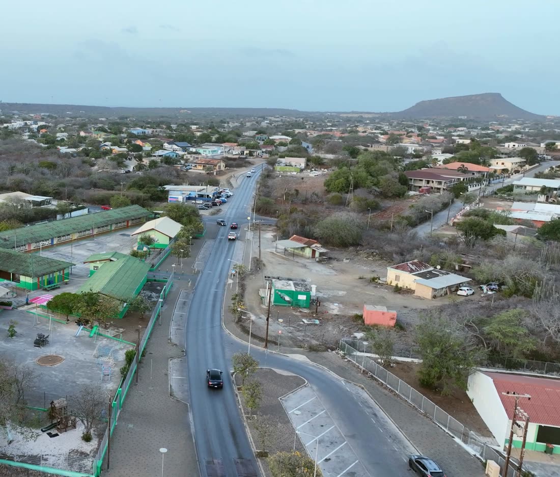 Dronebeeld van een woonwijk op Curaçao met heuvels aan de horizon